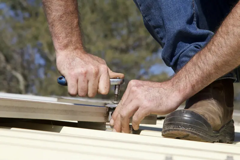 Hands fastening a metal roof panel