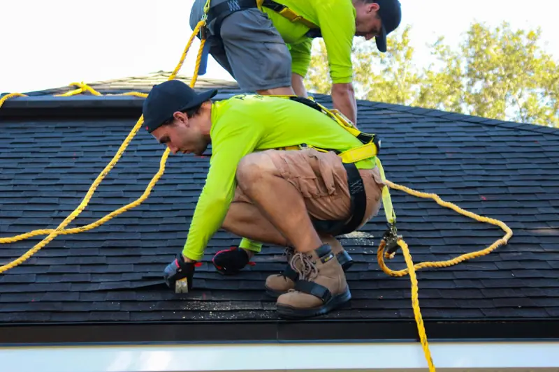 Two roofers working on a shingle roof